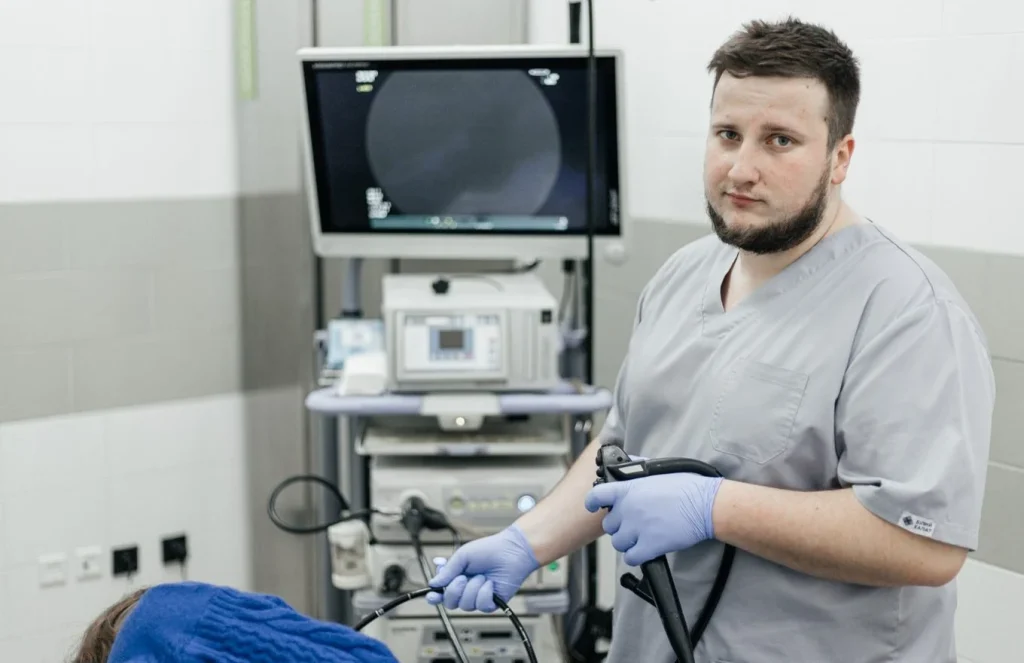 Лікар-ендоскопіст з ендоскопом біля стійки апаратури