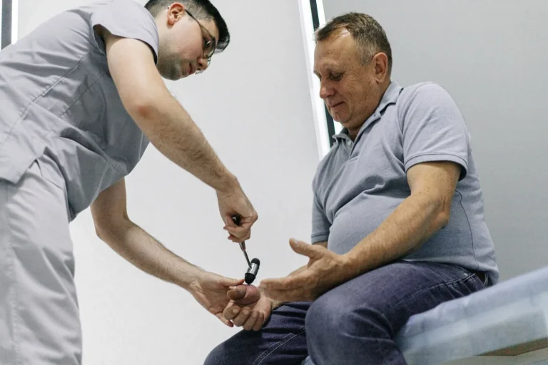 Лікар перевіряє рефлекси пацієнта неврологічним молоточком, медична мережа ЕКСПЕРТ