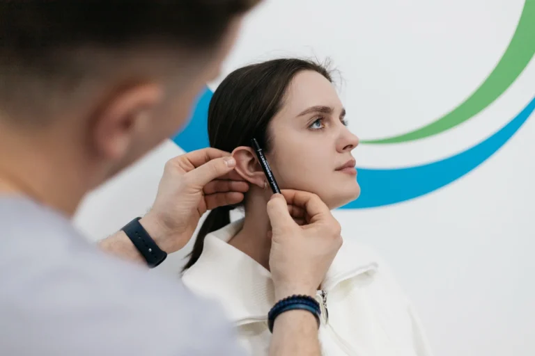 Лікар оглядає вухо пацієнтки та позначає лінії на консультації